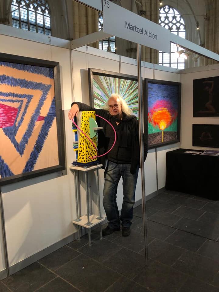 Martcel Albion at art exhibition with displayed artworks